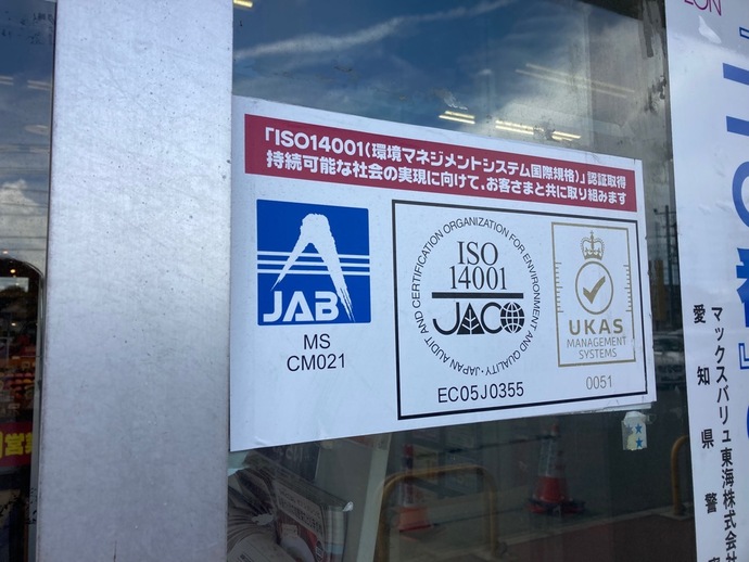 ISO14001(環境マネジメントシステム国際規格)の認証取得表示が店舗入り口に掲示されている写真