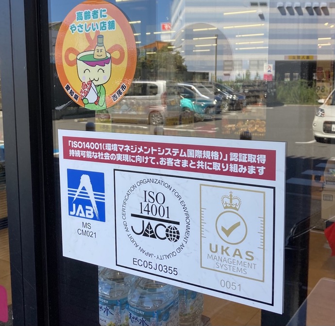 ISO14001(環境マネジメントシステム国際規格)の認証取得表示が店舗入り口に掲示されている写真